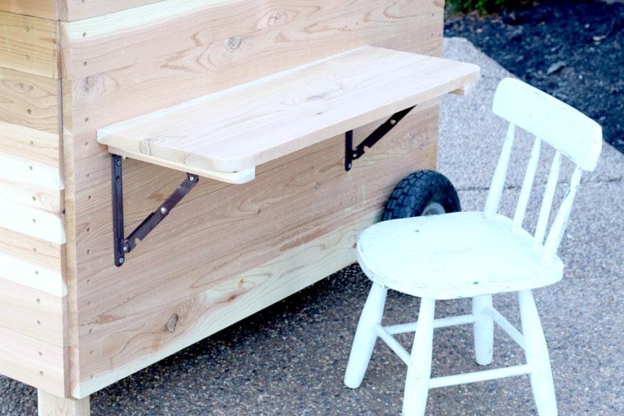 Outdoor party station mobile cart featuring storage for a large cooler, drawer that pulls out and doubles as a serving tray, pipe towel bar, and kiddie table! So COOL!