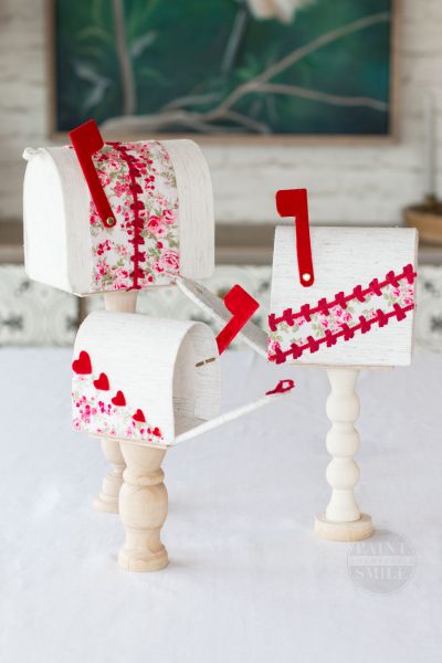 Easy DIY Valentines Mailboxes made from fabric, cardboard, and wooden candle sticks.