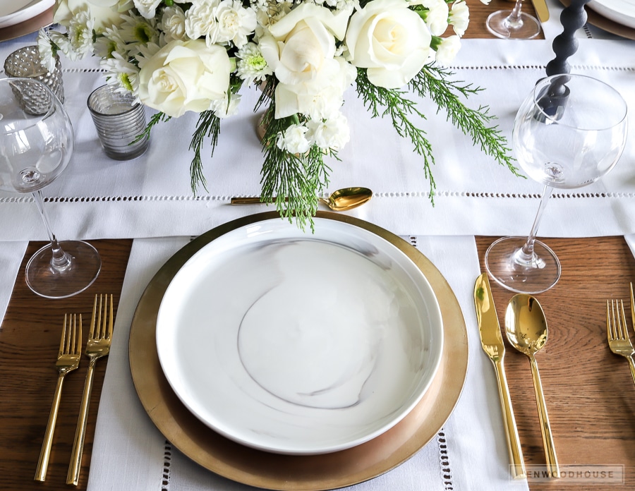 Winter White Christmas table setting with marble plates and gold flatware